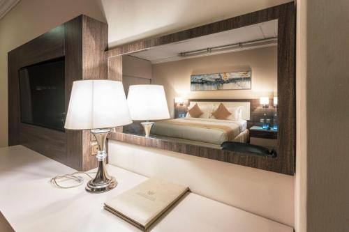 - une chambre avec un lit et un miroir dans l'établissement Hayat Al Riyadh Hotel, à Riyad