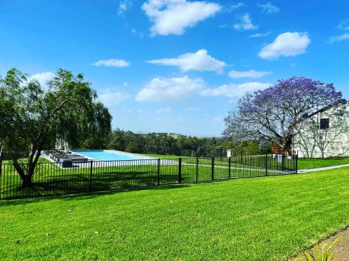 a field with a fence and trees at Wine Country Villas in Pokolbin