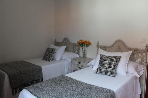 ein Schlafzimmer mit 2 Betten und einer Vase aus Blumen in der Unterkunft APARTAMENTO AROSA in Vilanova de Arousa