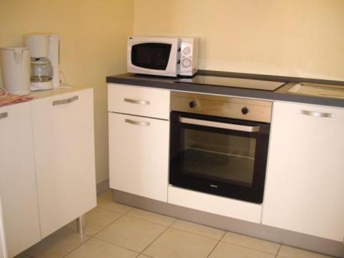 a kitchen with a microwave on top of a stove at La Rivière Meublé de Tourisme 2 étoiles in Laroche-Saint-Cydroine