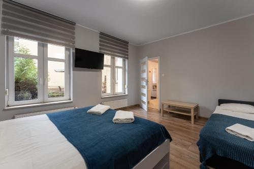 a bedroom with two beds and two windows at Sopot Host Garden in Sopot
