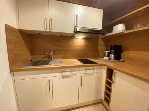 a small kitchen with white cabinets and a sink at Gatterhof in Riezlern