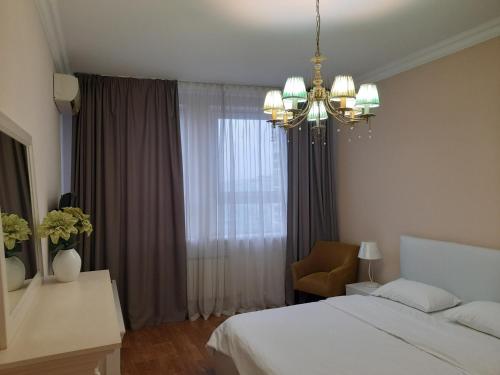 a bedroom with a bed and a chandelier and a window at BestKievApartment in Kyiv