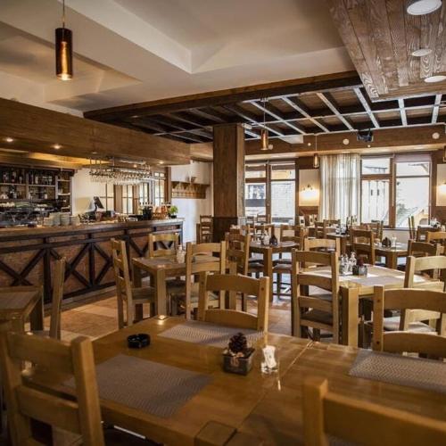 a restaurant with wooden tables and chairs and a bar at Hotel Villa Ugar Vlašić in Vlasic