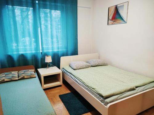 a bedroom with two beds and a window with blue curtains at Green Kabaty Apartment in Warsaw