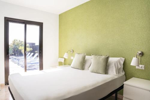 1 dormitorio con 1 cama blanca grande y paredes verdes en 3 Bedroom Villa Pool Short walk from Papagayo Beach, en Playa Blanca