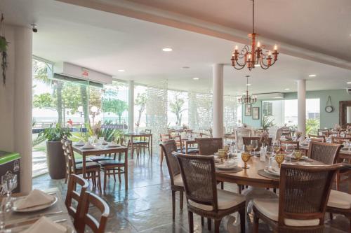 a dining room with tables and chairs and a chandelier at Hotel VillaReal Guaratuba - Caieiras in Guaratuba