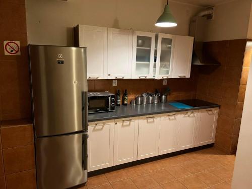 a kitchen with a stainless steel refrigerator and white cabinets at 50 People Bis Apartment in Kraków