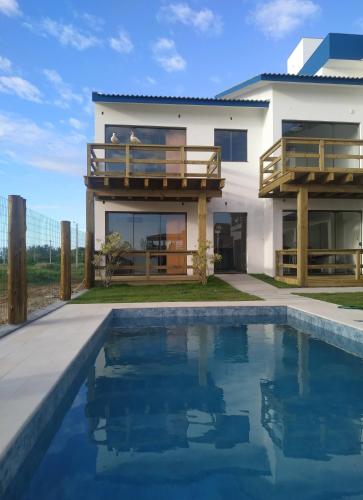 a house with a swimming pool in front of a house at Bella Ciao Hospedaria in Passo de Torres