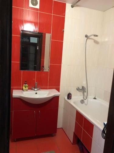 La salle de bains rouge et blanche est pourvue d'un lavabo et d'une baignoire. dans l'établissement 1кім в Центрі,вул.Набережна, à Rivne