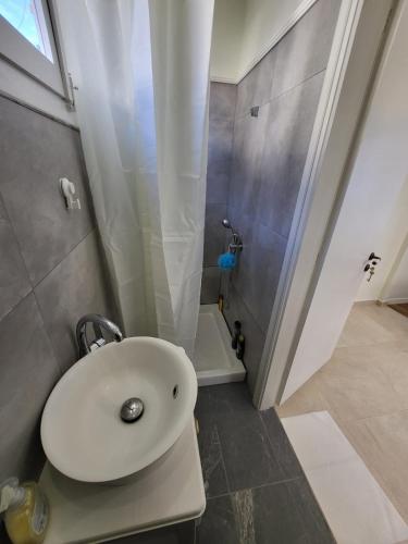 bagno con lavandino bianco e doccia di Lefkada Triola Apartments a Città di Lefkada