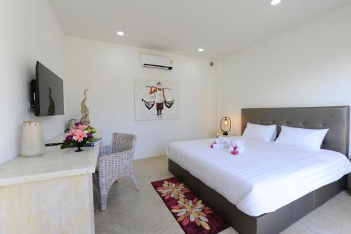 Dormitorio con cama, escritorio y TV en Barong Resort en Ban Phe