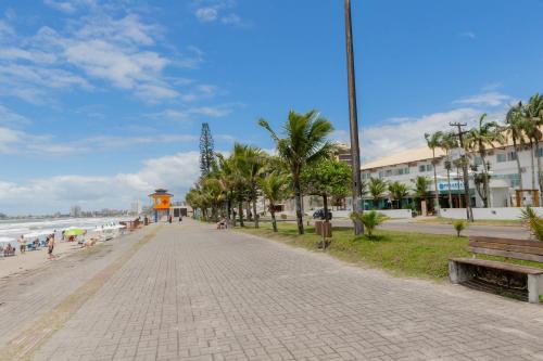 a sidewalk next to a beach with palm trees at Hotel VillaReal Guaratuba - Caieiras in Guaratuba
