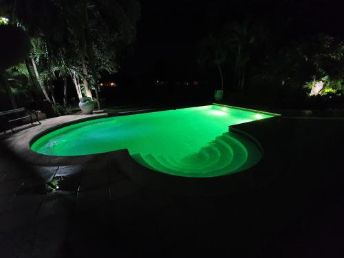 a swimming pool with green water at night at Villa M-6 Metro Country Club in Juan Dolio