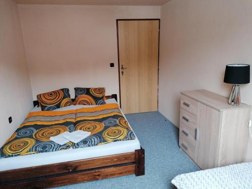 チェルニー・ドゥールにあるChata Roudnyのベッドルーム1室(ベッド1台、木製ドレッサー付)
