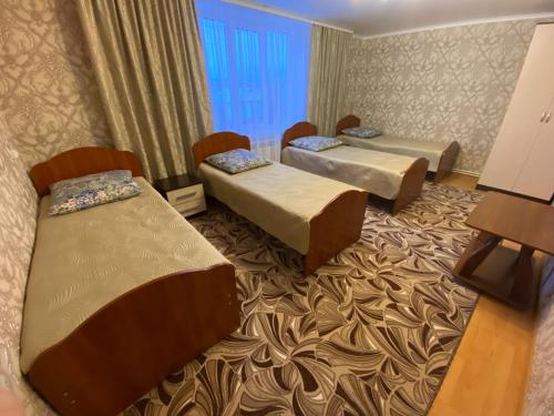 a hotel room with three beds and a window at Guest house Vostochnaya 27 in Diveyevo