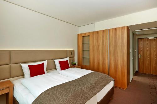 a bedroom with a large bed with red pillows at H4 Hotel München Messe in Munich