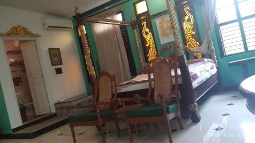 a bedroom with a canopy bed and two chairs at Indeco Hotels Swamimalai in Kumbakonam