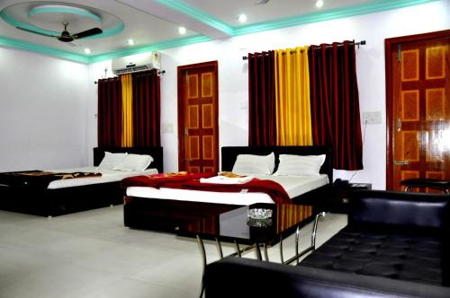 - 2 lits dans une chambre avec des rideaux et des chaises dans l'établissement MADHU MAMATA HOTEL, à Tarapith