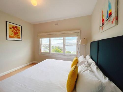 1 dormitorio con 1 cama blanca grande y ventana en Spectacular Hobart River View Home, en Lindisfarne