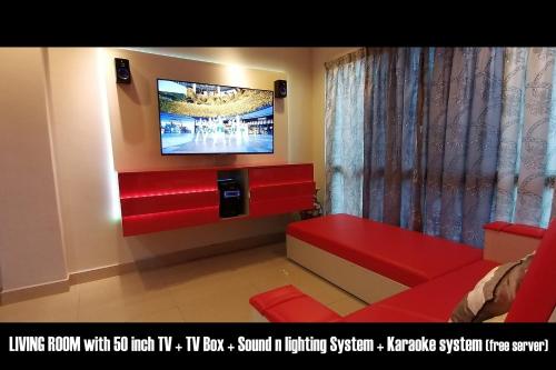 sala de estar con TV y sofá rojo en Penang karaoke Ruby Townhouse 1st floor, en Bayan Lepas