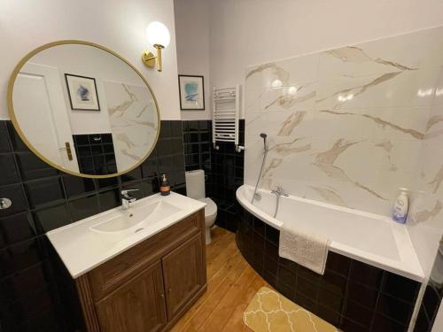 a bathroom with a sink and a tub and a mirror at Willa 1936 , Parking in Toruń