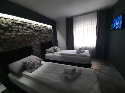 two beds in a room with a stone wall at Green Garden Zvonex Tuzla in Tuzla