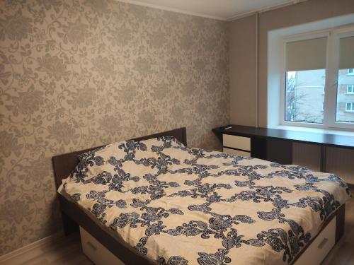 a bedroom with a bed with a blue and white comforter at VA Apartments in Rēzekne