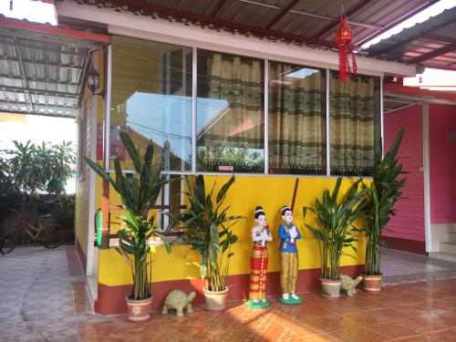 two figurines standing in front of a building with plants at บุญจินดา รีสอร์ท in Ban Phayom