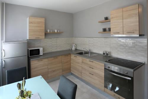 a kitchen with wooden cabinets and a stainless steel appliance at Studio apartman Ana in Osijek