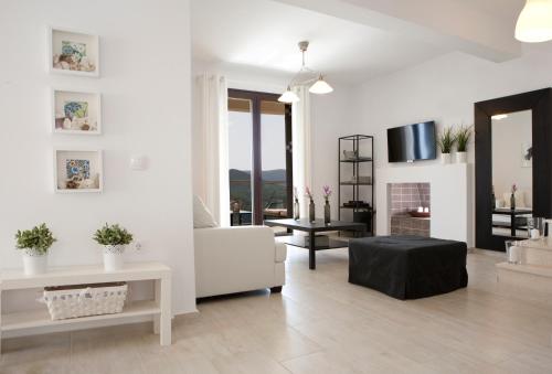 a living room with white furniture and a fireplace at Heavenly Heights Villas By KB Hospitality in Évyiros