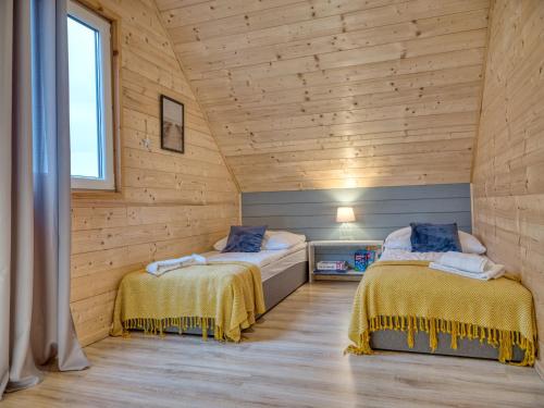 two beds in a room with wooden walls at MikroKlimat in Jarosławiec