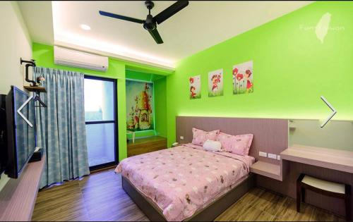 a green bedroom with a bed and a desk at 澎湖寶貝民宿 in Huxi