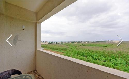 a window with a view of a field at 澎湖寶貝民宿 in Huxi