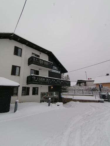 a building with snow on the ground in front of it at Hotel Pohorje in Maribor