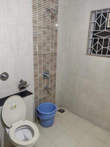 a bathroom with a toilet and a blue bucket at Guesthouse Sakina Colva in Colva