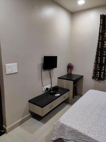 a bedroom with a bed and a table and a tv at Guesthouse Sakina Colva in Colva