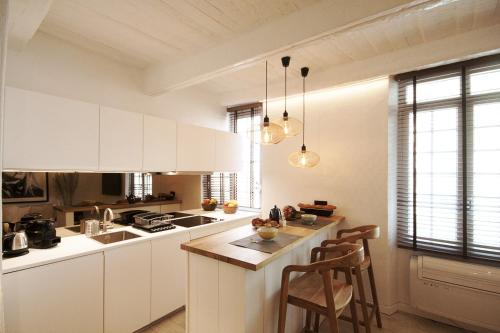 une cuisine avec des placards blancs et un îlot avec des chaises dans l'établissement Luxueux appartement, centre historique 50m du port et de la plage de la Ponche, à Saint-Tropez