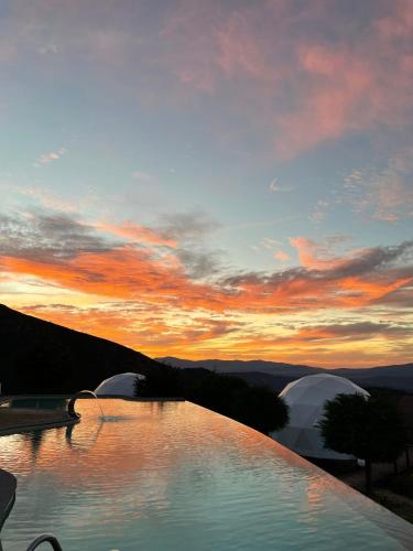 a view of a pool with a sunset in the background at Natura Glamping in Alcongosta