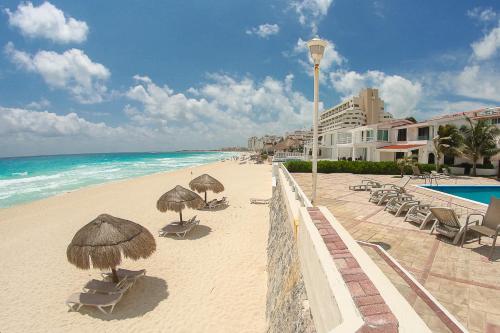 a beach with umbrellas and chairs and the ocean at Brisas Shores Beach & OceanFront Apartments 1 or 2 bedrooms Cancun Hotel Zone in Cancún