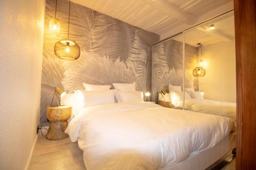 une chambre avec deux lits blancs et un miroir dans l'établissement Luxueux appartement, centre historique 50m du port et de la plage de la Ponche, à Saint-Tropez