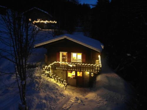 una casa cubierta de luces de Navidad en la nieve en Petit chalet rustique et bucolique en Bovernier