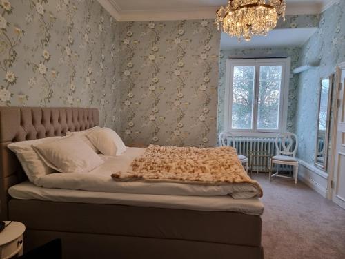 a bedroom with a bed and a chandelier at Anno 1908 Torpshammars Herrgård in Torpshammar