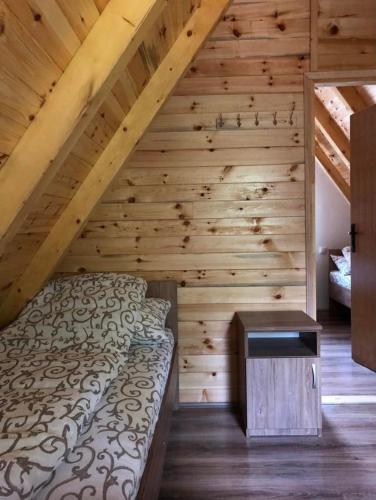a bedroom with a bed and a wooden wall at Planinska kuca ANDJELA 1 in Mitrovac