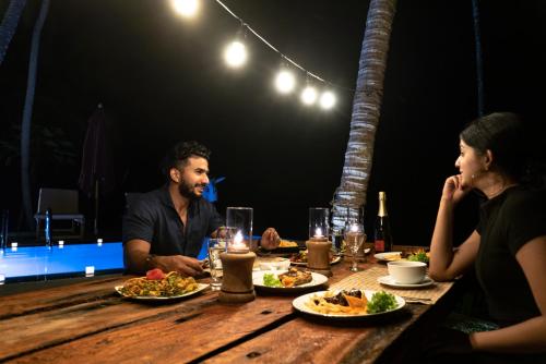 a man and a woman sitting at a table with food at Coconut Escapes in Kurunegala