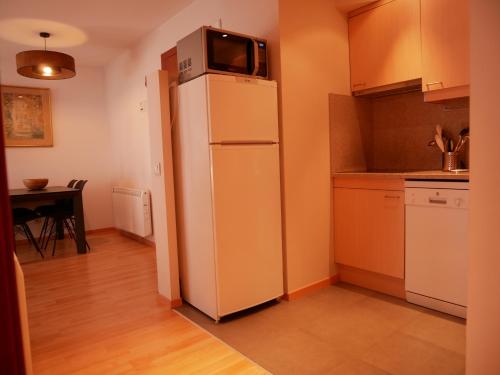 a kitchen with a refrigerator with a microwave on top of it at Solana-El Tarter in El Tarter