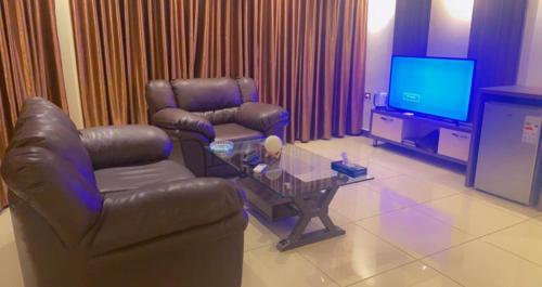 a living room with a leather couch and a tv at Seven Days Hotel in Irbid