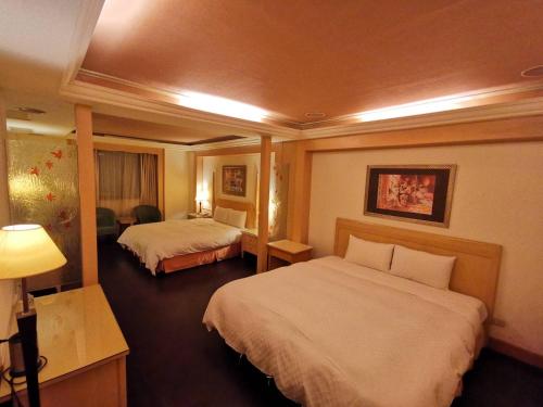 a hotel room with two beds and a desk at Mumu Motel in Guishan