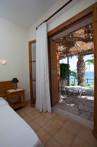 a bedroom with a bed and an open door at Grekis Beach Hotel and Apartments in Petalidhion