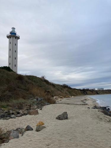 a lighthouse on a hill next to a beach at Аpartments Comfort -Marina Cape in Aheloy